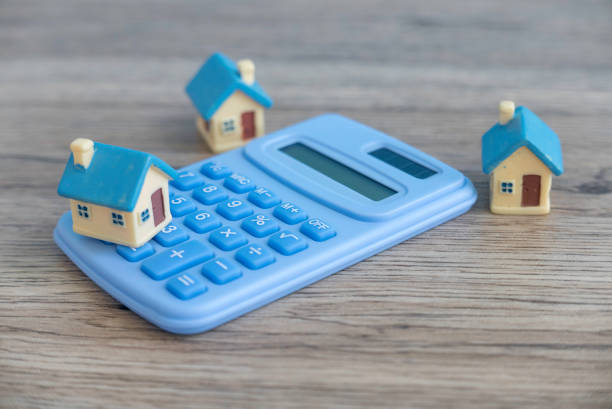 istock Financial Planning: A Miniature House on a Calculator Resting on a Table 2176196473
