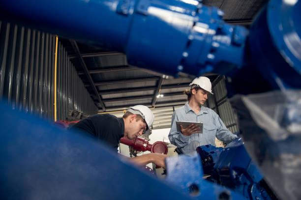 istock Engineer standing by robotic arm and operating machine in industry factory, technician worker check for repair maintenance electronic operation 2176211978