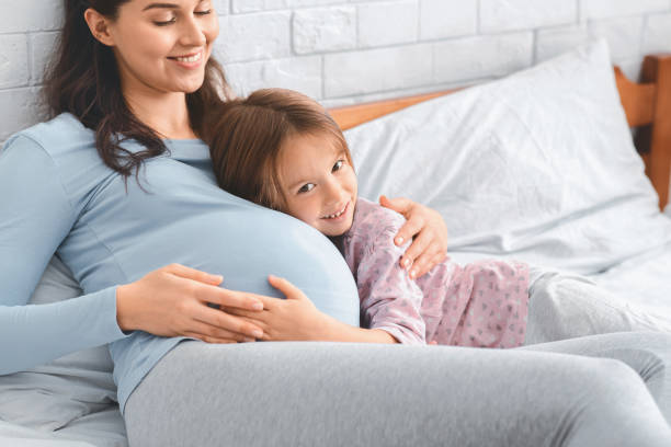 istock Little daughter and pergnant mother bonding on bed 2176214707