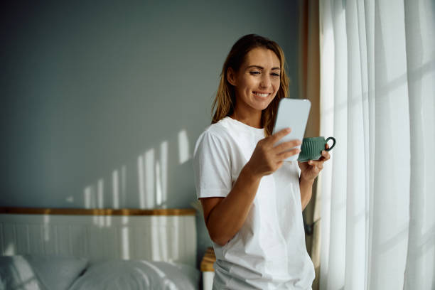 istock Happy woman using cell phone while enjoying in morning coffee. 2176214847