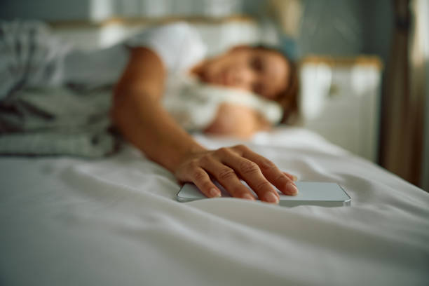 istock Close up of woman holding hand on her cell phone while sleeping. 2176214941