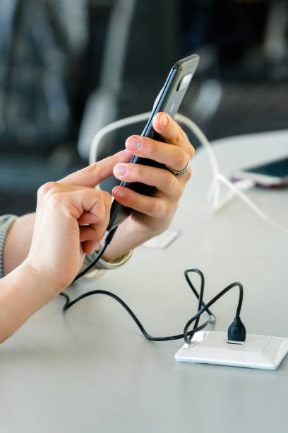 istock Close up of female hands charging smartphone using cord and usb plug in a public space while using a phone. 2176215196