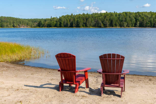 istock Two Red Adirondack Chairs on a Beach by Wolseley Bay 2176227506
