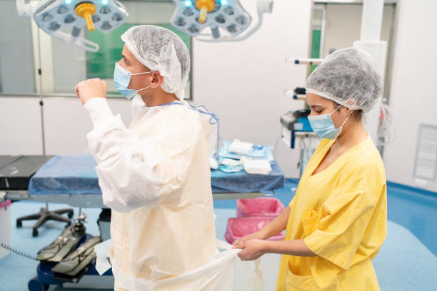istock Medical assistant assisting surgeon to get dressed in operation theatre 2176228364