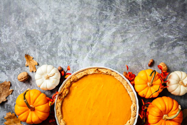 istock Pumpkin pie on a plate with autumn oak leaves, nuts, acorns, pumpkins on grey stone table. Flat lay, top view. 2176235172