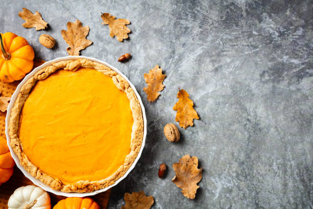 istock Pumpkin pie on a textured gray surface, surrounded by autumn leaves, mini pumpkins, acorns, and nuts. Thanksgiving and fall-themed culinary concept. 2176235228