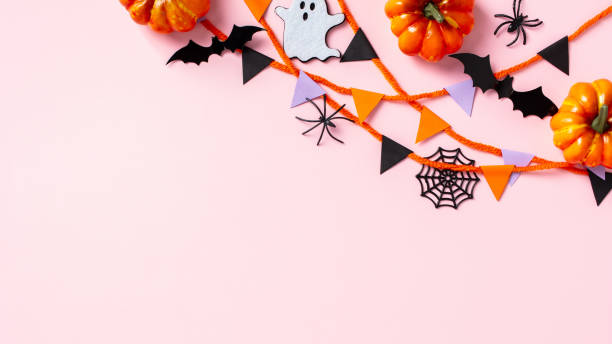 istock Halloween decor, pumpkins, ghost, bats, spiders, and garland on pink background. Flat lay, top view. 2176239449