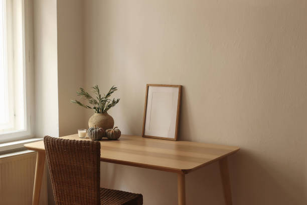 istock Elegant autumn interior. Vase with olive branches, pumpkins. Empty vertical picture frame mockup. Wooden table desk near window. Home office. Scandi interior. Cup of tea, coffee, candle. Beige wall 2176240696