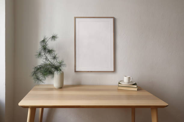 istock Christmas Scandinavian interior. Minimal winter home decor composition. Blank vertical wooden picture frame mockup hanging on beige wall. Cup of coffee, tea. Pine tree branches, vase on wooden table. 2176240704