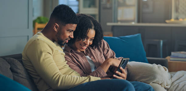 istock Beautiful Young black Couple Using Mobile Phone And Embracing Together At Home 2176240718