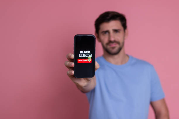 istock Man showing smartphone with black friday discount on screen 2176247345