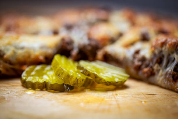 A homemade thin crust bacon cheeseburger pizza with pickles.