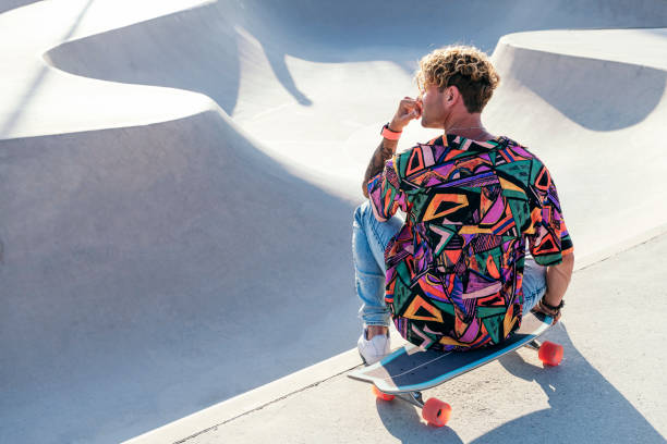istock guy with colorful shirt sitting on skateboard 2176267726