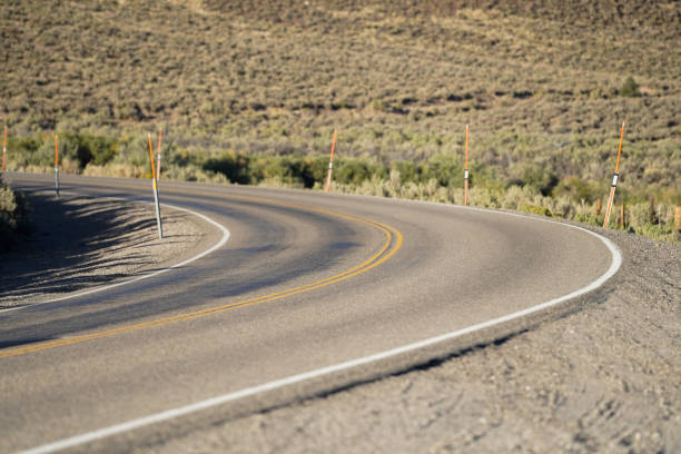 Curve in Nevada desert just before sunset with focus on double yellow lines in the center of the frame.