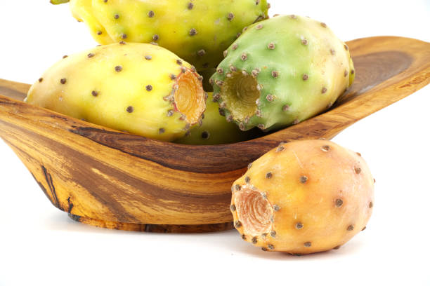 Colorful prickly pear fruit displayed in a wooden bowl, highlighting their natural texture and vibrant hues against a white backdrop