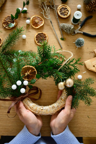 istock Hands crafting a Christmas wreath with pine and dried oranges 2176326681