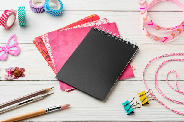 istock Crafting essentials on a workspace featuring a black notebook, colorful paper, and decorative supplies 2176327575