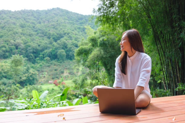 istock Portrait image of a woman using and working on laptop computer while sitting on balcony with a beautiful nature view 2176329891
