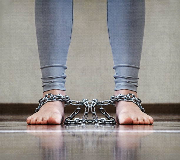 istock Lower Legs Shackled With Heavy Metal Chains Gray Background 2176331732