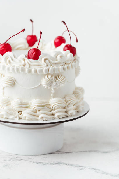 istock Delicate lambeth style birthday cake with white cream cheese frosting decorated with cocktail cherries on the white background 2176331907