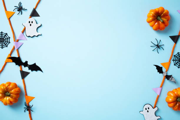 istock Halloween party decorations on pastel blue background. Frame of pumpkins, ghost, bats, spiders, and garland 2176335235