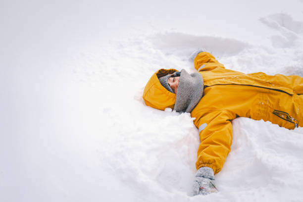 A joyful child in a bright yellow coat playing in fresh snow during winter's frosty embrace
