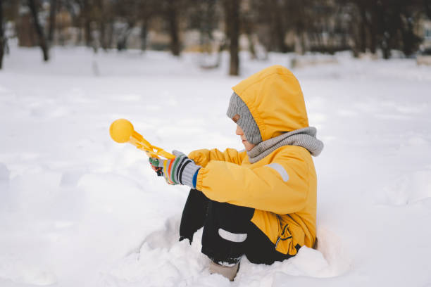 istock Young boy playing with a snowball maker in a cold winter day 2176337346