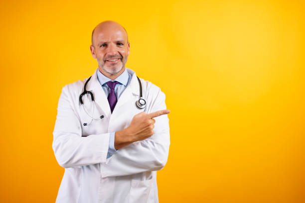 istock A doctor in a white coat with a stethoscope smiles and points to his right. 2176340917