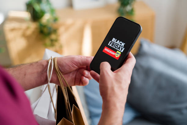 istock Man holding shopping bags using smartphone for black friday shopping 2176346348