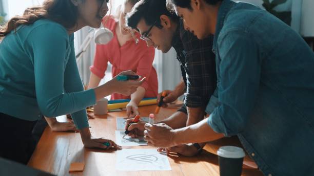 istock Top view of skilled designer holding logo while discussing with team. Symposium. 2176351470