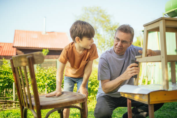 istock Boy and his grandfather sanding a chair outdoors at back yard in sunny evening. 2176351608