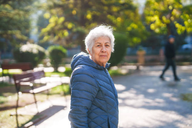 Portraits of a senior woman, walking in a public park during day.