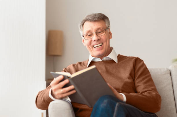 istock Senior Man Reading Book Sitting On Sofa At Home 2176353089