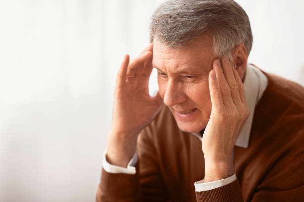 istock Elderly Gentleman Having Headache Massaging Temples Sitting Indoor 2176353116