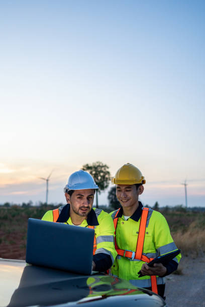 istock Diverse ethnicity male technicians working in the wind turbines field. Innovation engineer men use laptop computer work to develop environmental renewable clean energy outdoors at windmill power farm. 2176353324