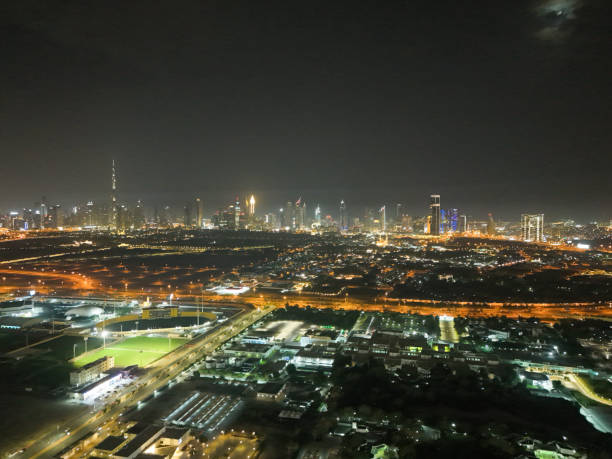A stunning night view of the Dubai skyline and glowing city lights. Illuminated highways and streets lead to the vibrant city center.