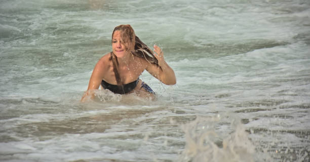 Girl in a shallow sea crushed by large waves, Bali, Indonesia