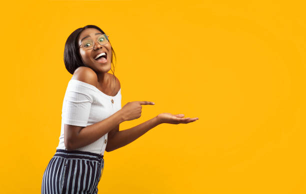 istock Excited Girl Pointing Finger At Open Palm Standing, Orange Background 2176355605