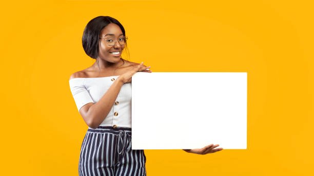 istock Millennial Girl Holding White Board Smiling Standing, Orange Background, Panorama 2176355632