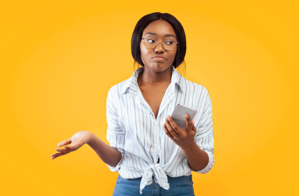 istock Discontented Afro Woman Holding Smartphone Shrugging Shoulders, Pink Studio Background 2176355718
