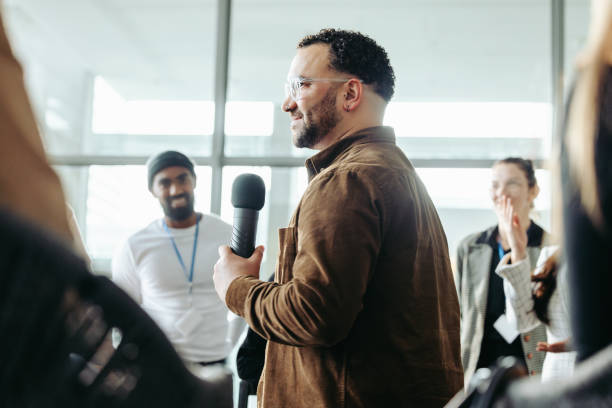 istock Confident business owner leading a team training session with a microphone in a modern office setting, promoting leadership and teamwork 2176357381
