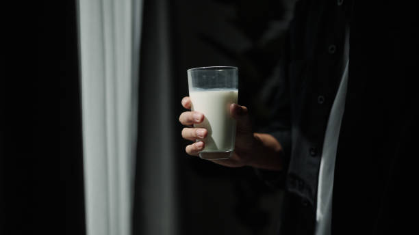 Close-up hand holding a glass of milk.
