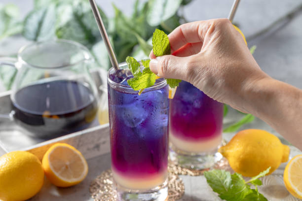 Lemonade with blue and violet butterfly pea flower tea on light gray background with copy space