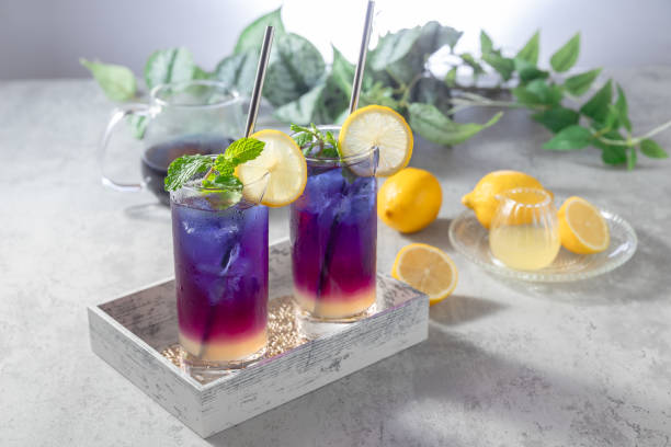Lemonade with blue and violet butterfly pea flower tea on light gray background with copy space