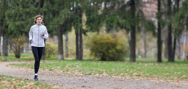 istock Woman Jogging Along the Path in a Park During Autumn 2176364896