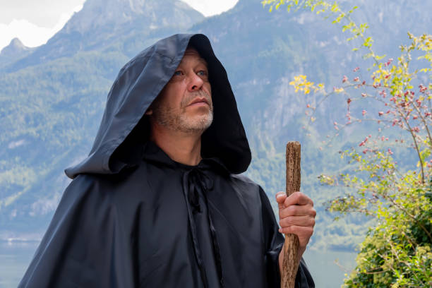 A monk in a black robe against a mountain landscape.