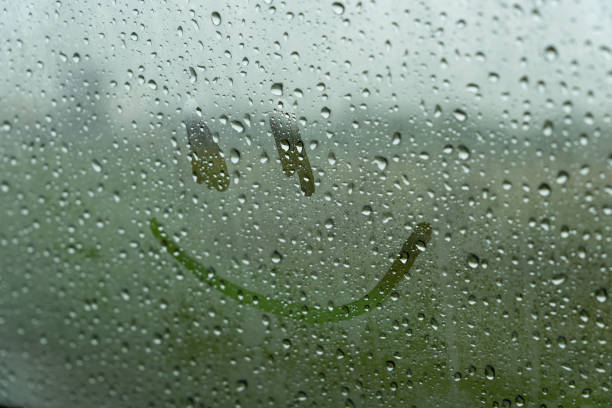 istock Raindrops create a textured surface on the glass, while a cheerful smiley face is drawn amidst the droplets, brightening the gloomy afternoon outside 2176369785