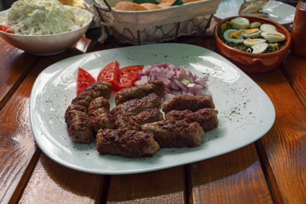 istock Balkan cuisine. Cevapi - grilled dish of minced meat - with vegetables on rustic table 2176378806