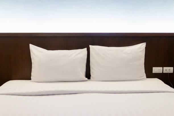 istock Cozy bedroom with two crisp white pillows on a neatly made bed. 2176379361
