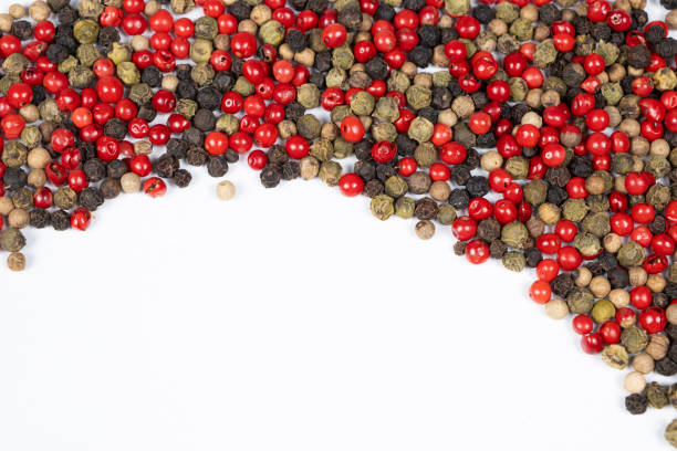 Various types of red, black pepper and dried thyme seeds. Assortment of scattered spices in a spoon on a wooden board. Selective focus